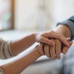 A man and a woman holding each other hands for comfort and sympathy