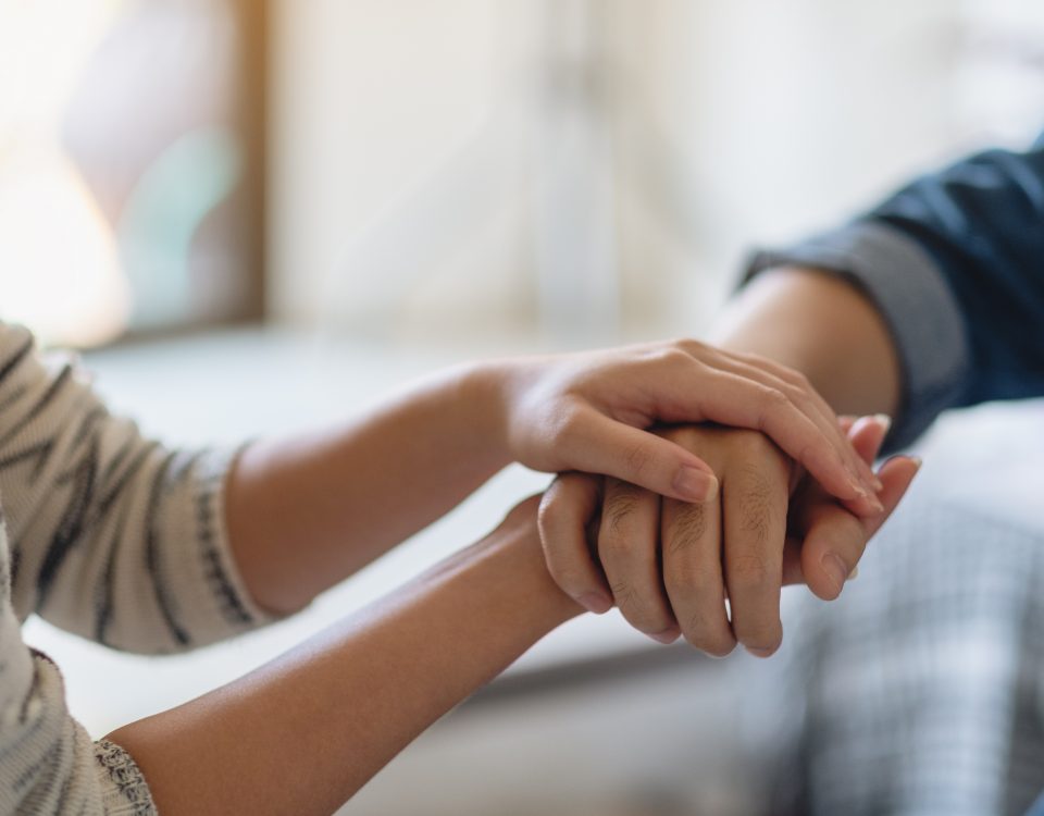 A man and a woman holding each other hands for comfort and sympathy